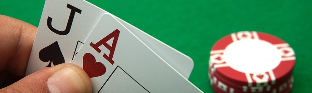 An A and J being shown by the player with chips and a green poker table in the background