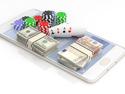 a mobile phone with casino chips, cards, and cash sitting on it